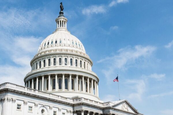 Picture of US Capitol Dome against a blue sky with American flag flying