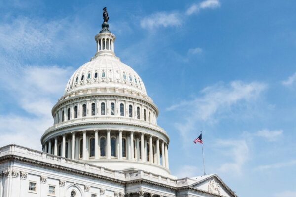 Picture of US Capitol Dome against a blue sky with American flag flying